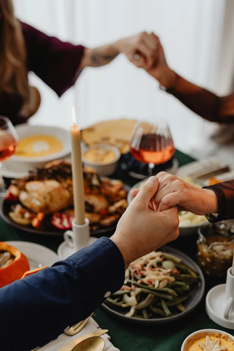 Hands joined around a table set for a shared meal.